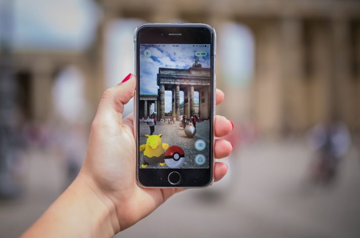 A woman points her smart phone at the Brandenburg Gate as she plays the Pokemon Go mobile game in Berlin on July 13, 2016. The Pokemon Go mobile gaming craze reached European fans with players in Germany the first to get their hands on the augmented reality sensation. / AFP PHOTO / dpa / Sophia Kembowski / Germany OUT